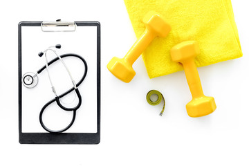 Sport and health. Fitness. Dumbbells and stethoscope on white background top view