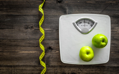 Lose weight concept. Bathroom scale, measuring tape, apples on wooden background top view copyspace