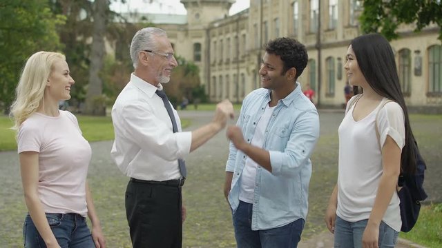 Friendly teacher giving high five to his multiracial group of students, teamwork