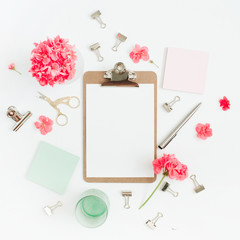 Flat lay home office desk. Clipboard with copy space for text, red flowers, accessories, mint diary on white background. Top view mock up women background.
