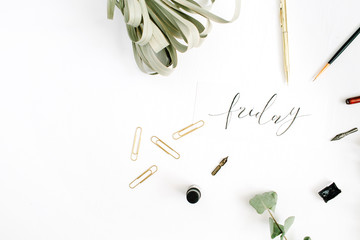 Word Friday written with calligraphy on white background with pen, brush, eucalyptus and clips. Flat lay, top view.