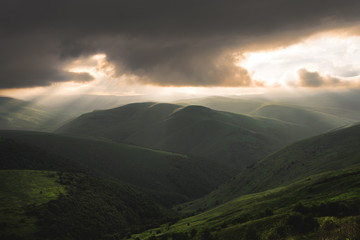 Obraz premium Beautiful Caucasian hilly green valleys with low clouds and rays of the setting sun