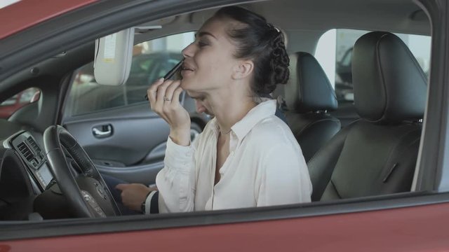 Beautiful businesswoman paint lips with lipstick in the car