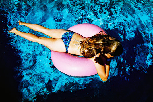 girl in bikini on pink floatie in pool