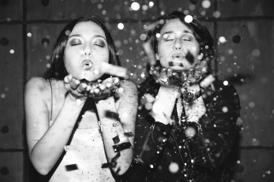 Two girls blowing glitter at camera