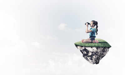 Concept of careless happy childhood with girl looking in binocul