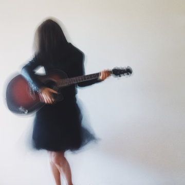 Cell phone photography - Unrecognisable woman holding a guitar, with intentional blur