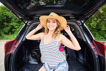 Naklejka premium Happy woman with luggage in car trunk. Travel concept