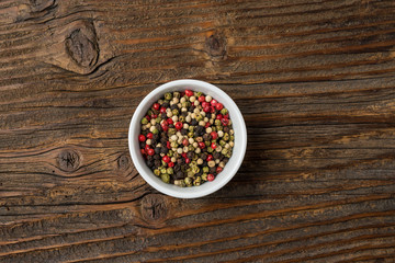 Colorful pepper in white bowl on an old wooden table