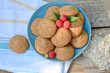 Oatmeal cookies in a bowl and raspberry next towel oatmeal