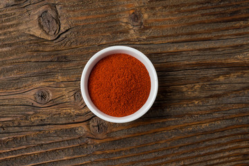 Paprika powder in white bowl on an old wooden table