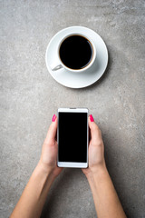 Woman holding smart phone over gray stone table