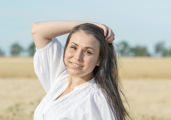 Beautiful sexy smiling female touching her long hair in wheat field