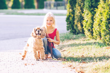 Little beautiful girl is walking with a dog in the park