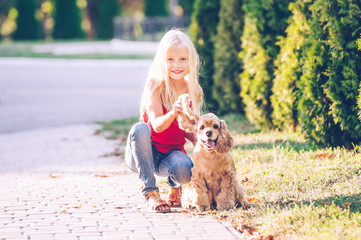Little beautiful girl is walking with a dog in the park