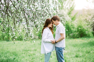 Fototapeta premium Portrait of lovely future parents during sunset on nature apple tree background