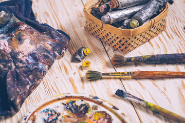 Oil paints and paint brushes on a palette close up.