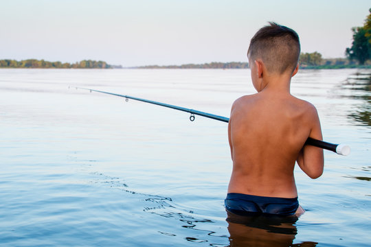 Boy fishing waist deep in water