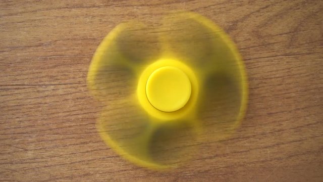 Playing with the yellow Fidget Spinner. Toy spinner.