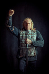 Powerful blond knight with the sword on the dark background