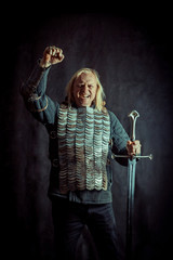 Powerful blond knight with the sword on the dark background