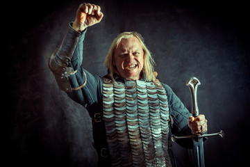 Powerful blond knight with the sword on the dark background