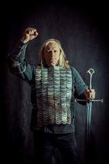 Powerful blond knight with the sword on the dark background