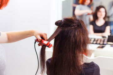 Fototapeta premium Stylist align the customer's hair with straightener