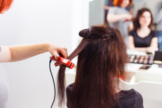 Stylist align the customer's hair with straightener