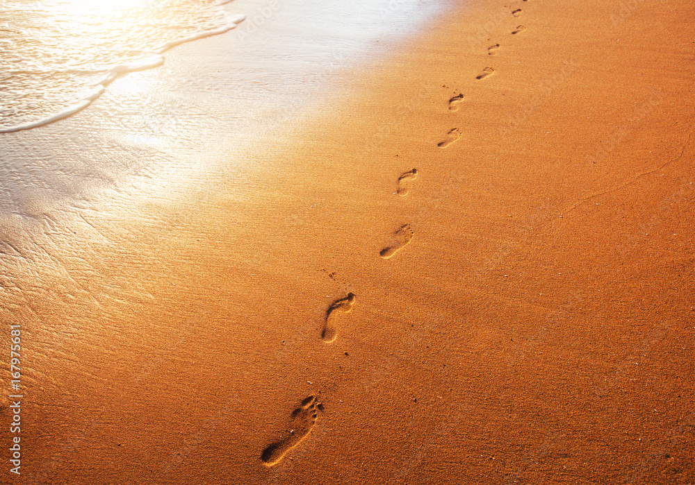 Wall mural beach, wave and footprints at sunset time