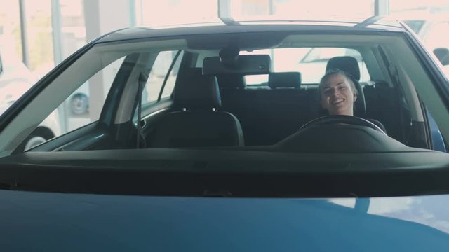 The woman uses automatic seat in the modern automobile in car showroom