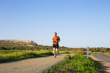 Man running outdoor sprinting for success. Male fitness runner sport athlete in sprint at great speed in beautiful landscape.