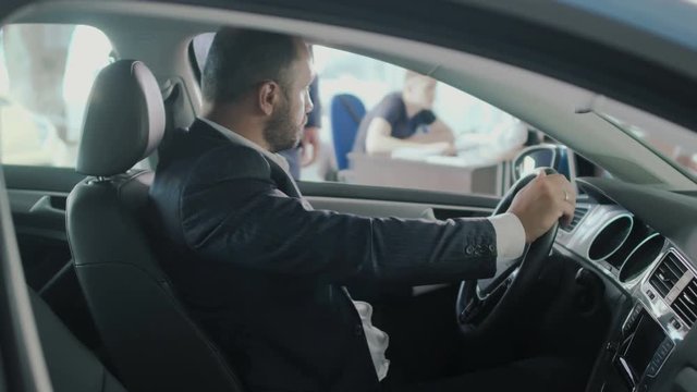 The businessman gets a car's keys from salesman on gyroscope in car dealership