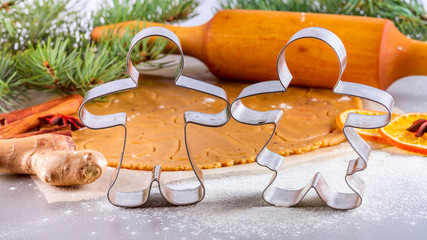 Christmas still life background - forms for gingerbread with silhouette of man and woman with ingredients for baking
