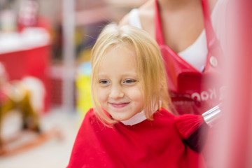 Little girl makes the haircut in the barber shop. Happiness.