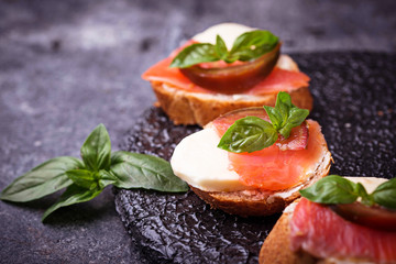 Crostini with salmon, mozarella, tomato and basil