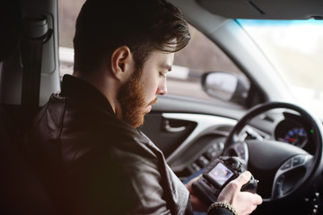 The man in the car reviews the photos on the camera. Spy, paparazzi, journalist, photographer.