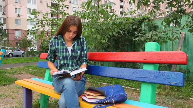 Beautiful student girl reading book outdoors