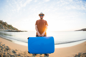 Fototapeta premium Man in sunglasses with luggage on the sea in summer sunny day