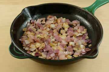 Sauteed chopped red onions in cast iron frying pan skillet