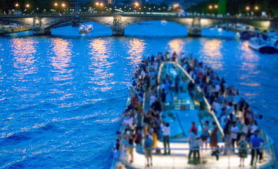 Fototapeta na wymiar Cruise with tourists sailing by Seine river at night in Paris, France