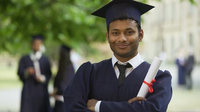 Serious graduate crossing arms with diploma in hand, completion of studies pride