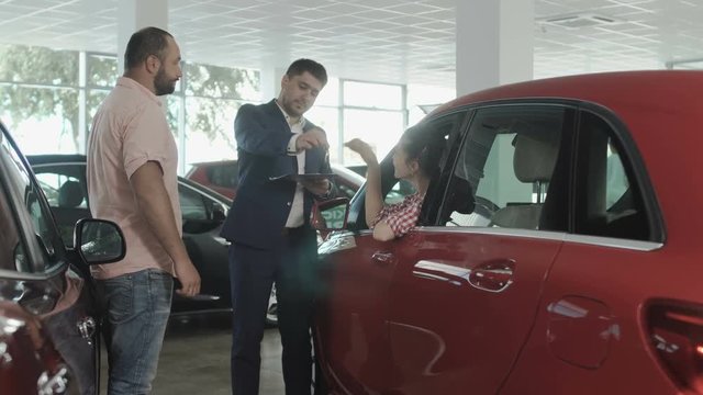 Happy couple buys a new automobile in the car dealership