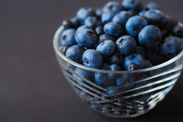 Fresh blueberries in white bowl on wood table, rustic style