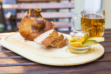 eisbein with bread, vegetables and beer on wooden cutting board