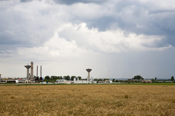 Industrial landscape with wheat field and dramatic clouds
