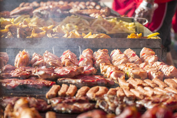 Different kind on grilled meat and sausages with smoke and steam from the grill