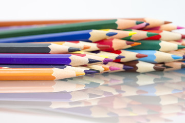 Group of sharp colored pencils with white background and reflexions