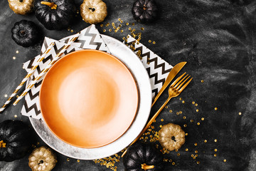 Halloween Table setting on dark background. Dish on a dark table with black and gold pumpkin. Flat...