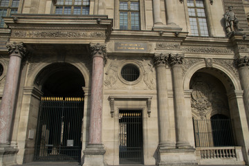 Inner courtyard and exterior of The Louvre Museum with walking tourists in a summer day